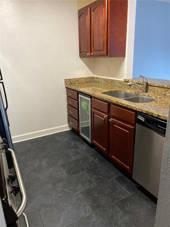 A kitchen features dark wood cabinets, granite countertops, a stainless steel dishwasher, and slate flooring — 2047 DIXIE BELLE DRIVE UNIT 2047H, ORLANDO, FL