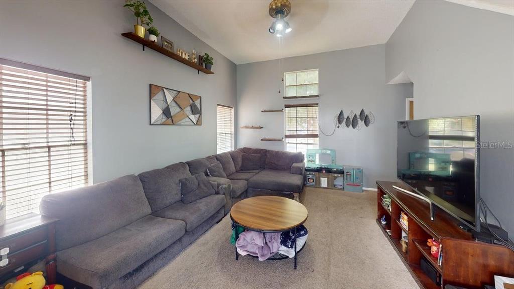 A living room features a large gray sectional sofa, a round coffee table, and a television — 7508 OKEECHOBEE COURT, TAMPA, FL