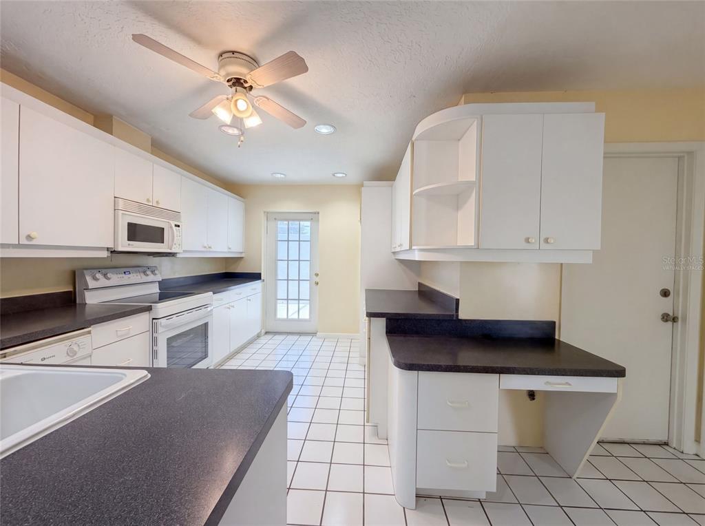 A kitchen with white cabinets, dark countertops, a tile floor, and a ceiling fan — 1301 LUCAYA AVENUE, VENICE, FL