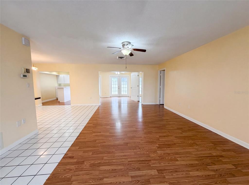 A living area with wood-look flooring, a ceiling fan, and an adjacent tiled kitchen — 1301 LUCAYA AVENUE, VENICE, FL