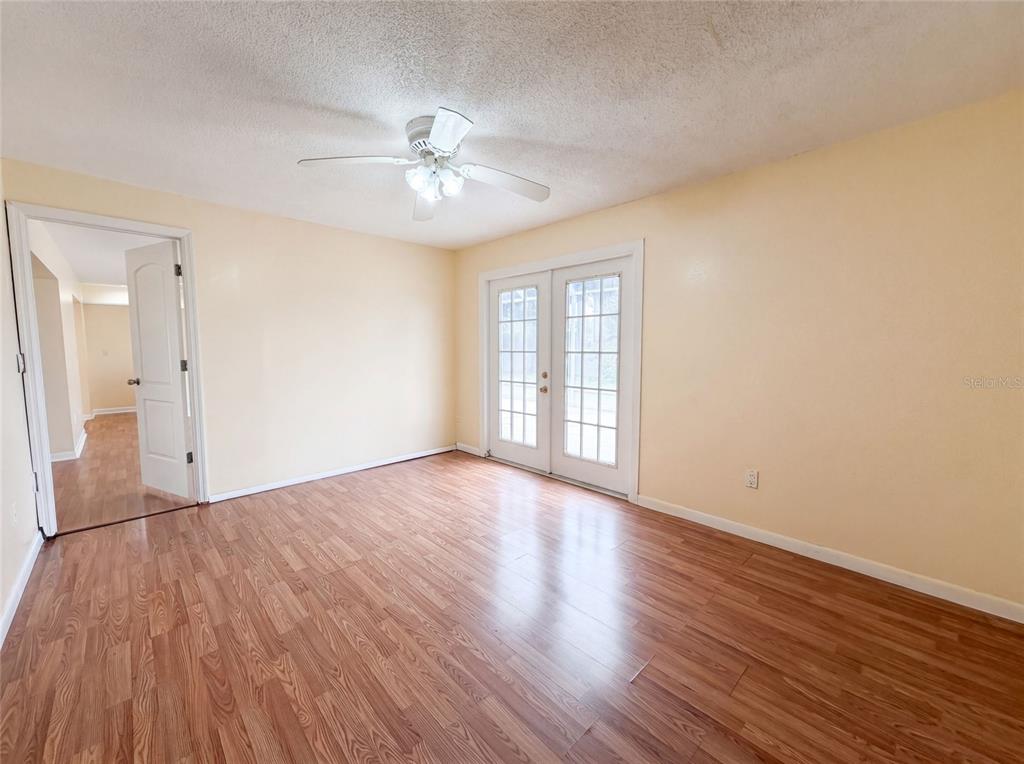 A room with light yellow walls, wood-look flooring, a ceiling fan, and glass-paned French doors — 1301 LUCAYA AVENUE, VENICE, FL