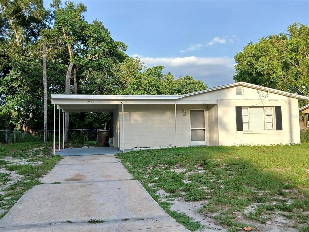 A single-story house with a concrete block exterior, a carport, and a front lawn — 930 EMERALD DRIVE, MOUNT DORA, FL