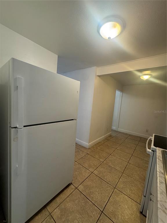 A white refrigerator stands in a kitchen with tiled floors and two ceiling lights — 930 EMERALD DRIVE, MOUNT DORA, FL