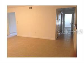 An interior view shows a room with light-colored tile flooring and doorways leading to hallways — 4166 VERSAILLES DRIVE UNIT 4166D, ORLANDO, FL