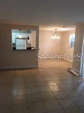 A living area with tile flooring looks toward a dining space and a kitchen pass-through — 4166 VERSAILLES DRIVE UNIT 4166D, ORLANDO, FL