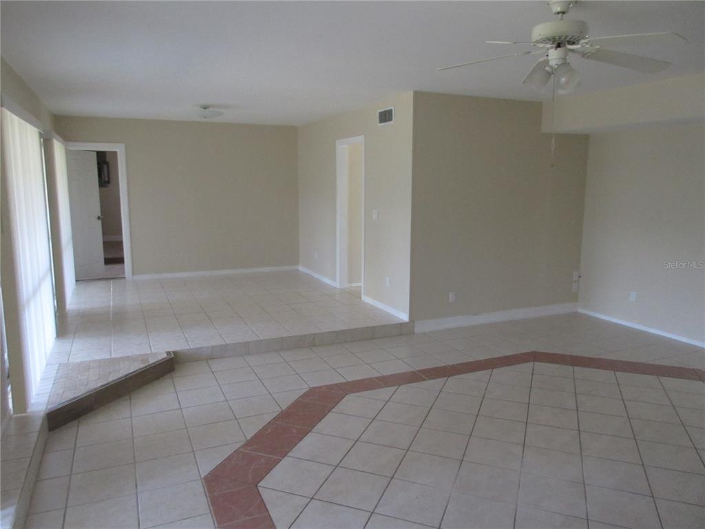 An interior view of a living area featuring beige tile flooring, a sunken section, and a ceiling fan — 1275 PRICE CIRCLE NW, PORT CHARLOTTE, FL