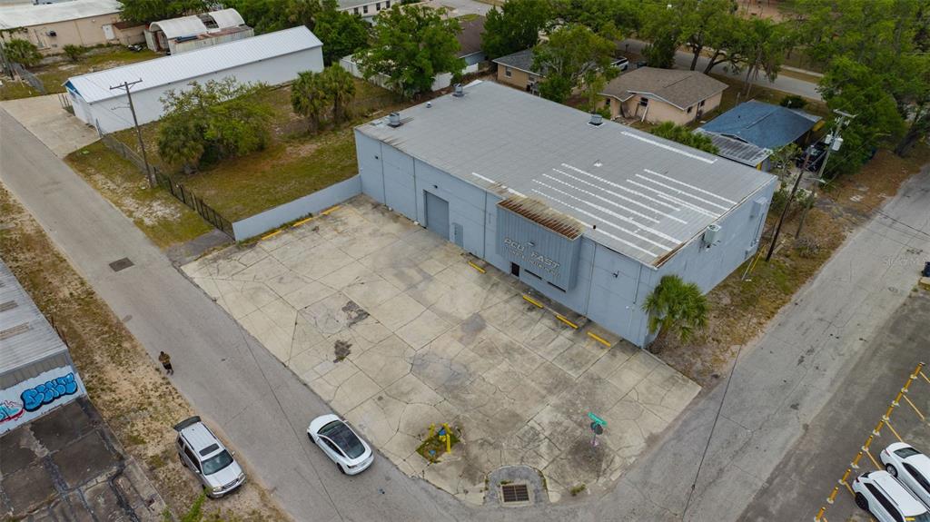 An aerial view shows a gray industrial warehouse building with a large concrete parking lot — 1001 E SKAGWAY AVENUE, TAMPA, FL