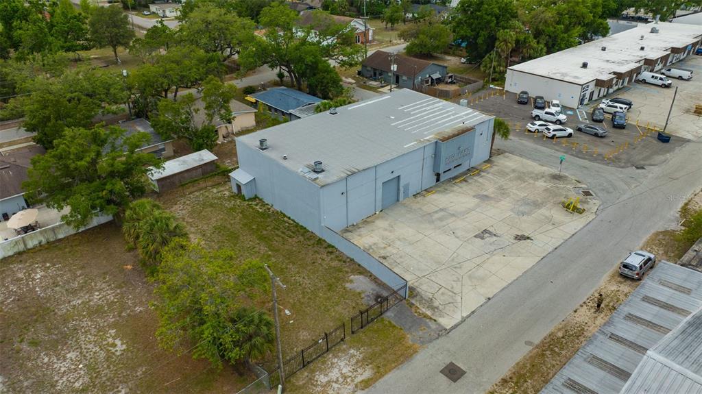 An aerial view shows a gray industrial building with a paved parking lot and adjacent land — 1001 E SKAGWAY AVENUE, TAMPA, FL