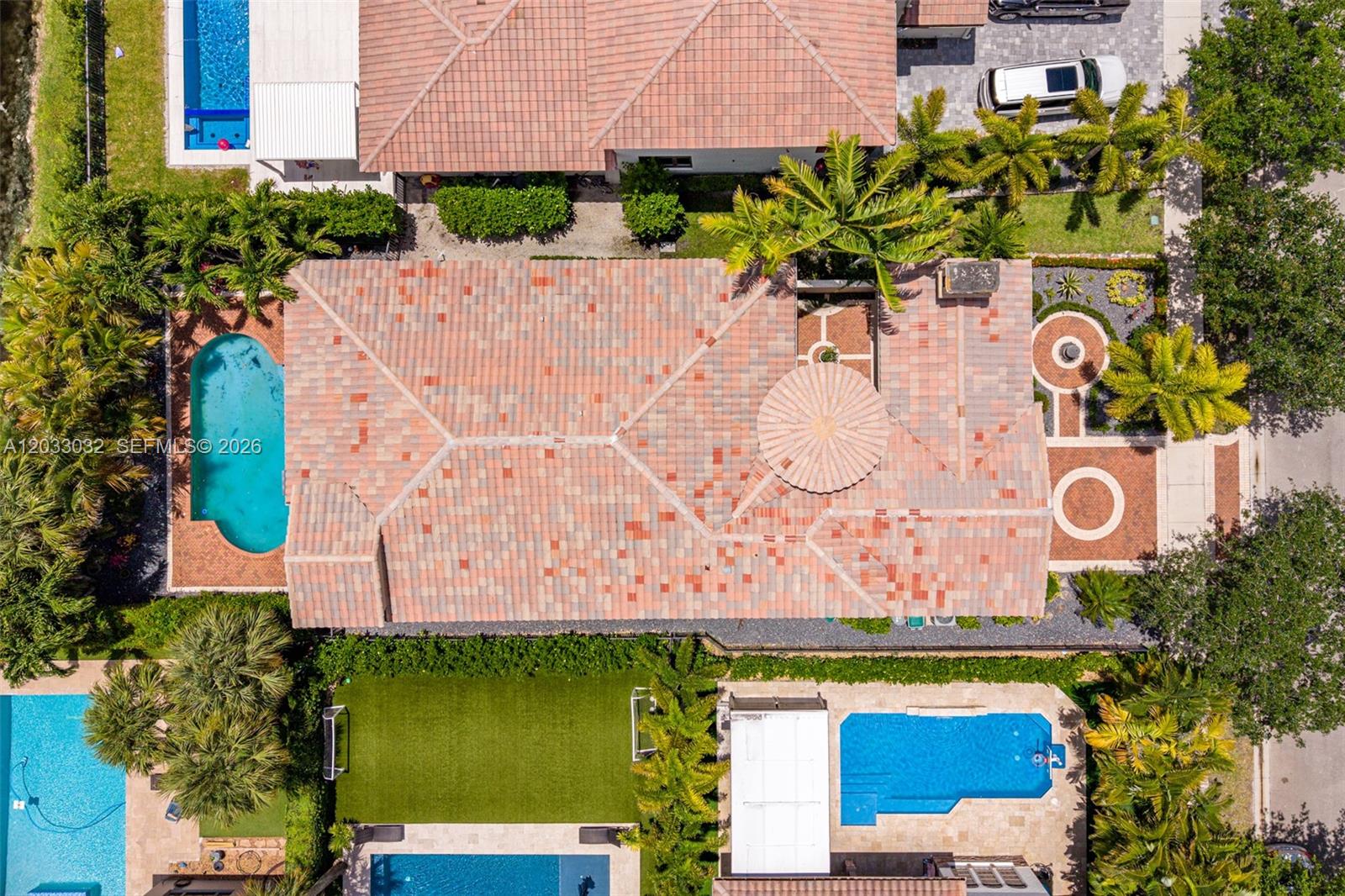 An aerial view shows a house with a tiled roof, two swimming pools, and landscaping — 9534 Ginger Ct, Parkland FL 33076, PARKLAND, FL