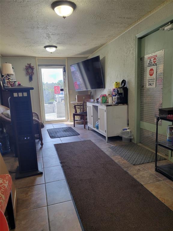 A room with tiled floors, a wall-mounted television, a coffee station, and an exterior door — 8783 E HIGHWAY 25, BELLEVIEW, FL