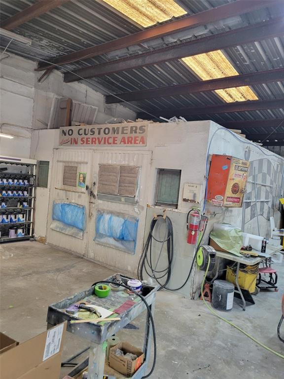 An industrial workshop features a paint booth with a sign reading no customers in service area — 8783 E HIGHWAY 25, BELLEVIEW, FL