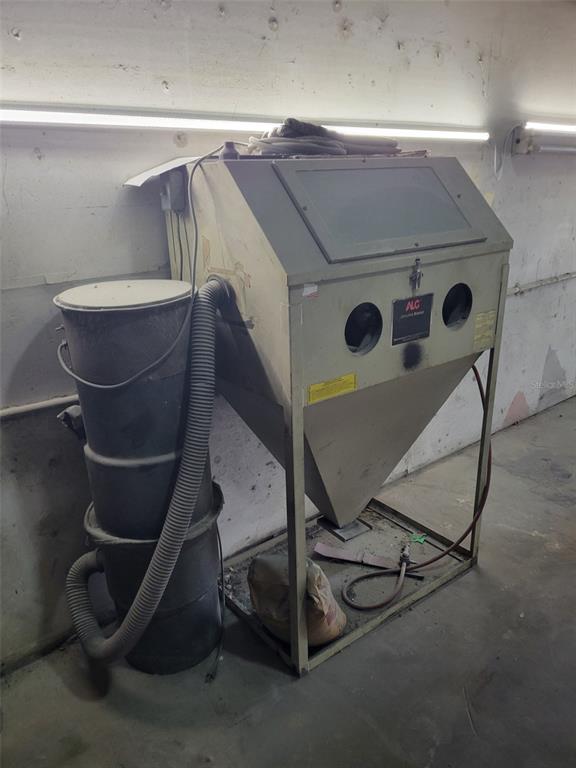 A sandblasting cabinet with an attached dust collection drum sits against a white wall — 8783 E HIGHWAY 25, BELLEVIEW, FL