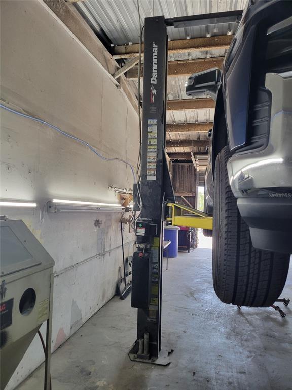 A vehicle is elevated on a Dannmar lift inside a garage with concrete walls — 8783 E HIGHWAY 25, BELLEVIEW, FL