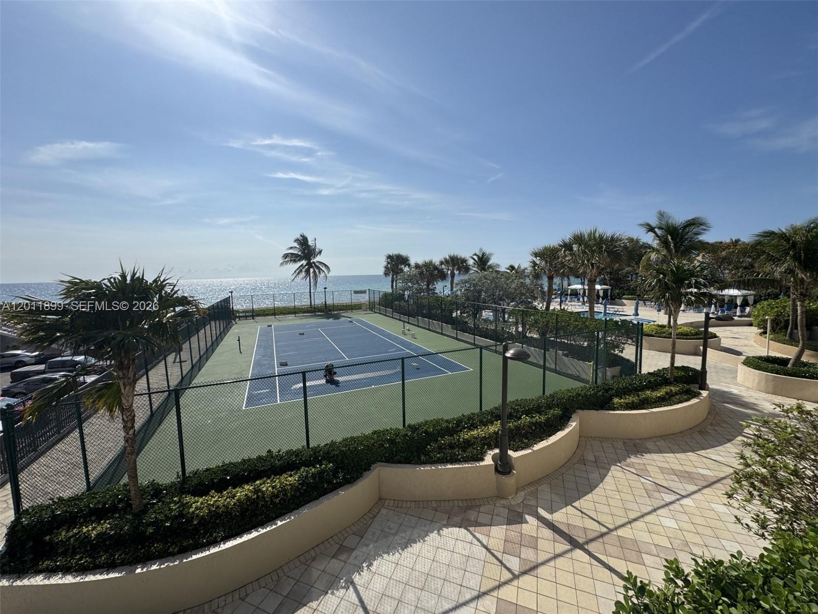 An outdoor tennis court sits adjacent to a paved walkway and the ocean — 1912 S Ocean Dr # 3D, Hallandale Beach FL 33009, HALLANDALE BEACH, FL