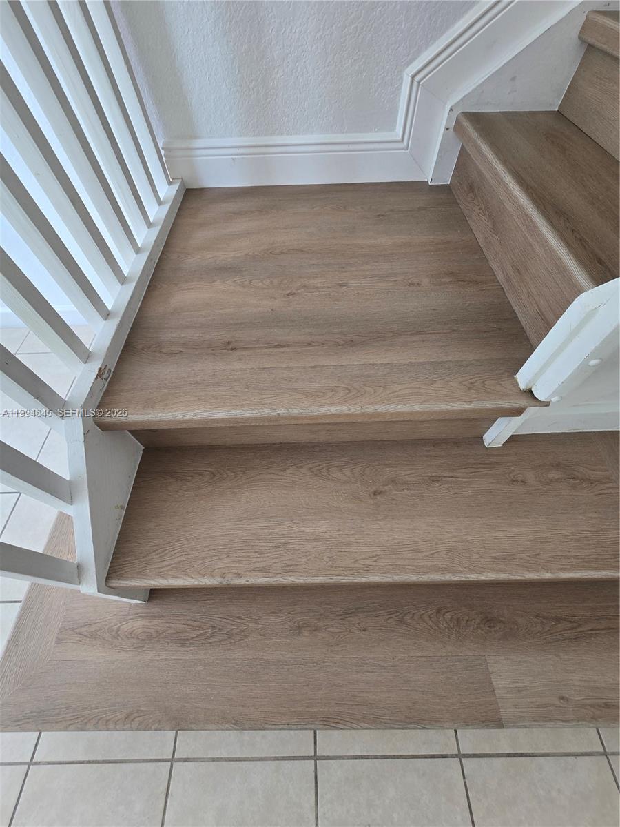 A staircase features wood-look vinyl treads and white railings above a tiled floor — 1575 NE 33rd Ave # 9, Homestead FL 33033, HOMESTEAD, FL