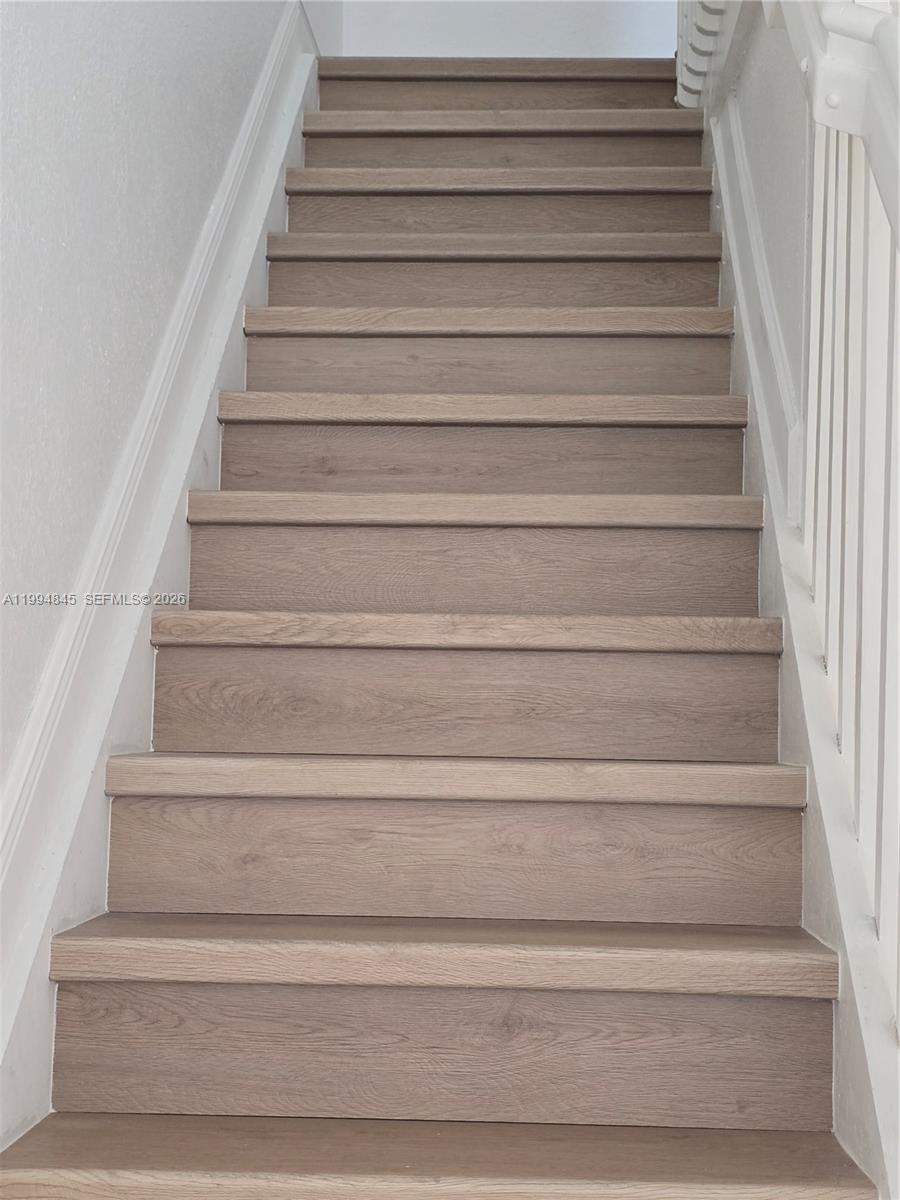 A straight wooden staircase features light brown treads and white side walls — 1575 NE 33rd Ave # 9, Homestead FL 33033, HOMESTEAD, FL