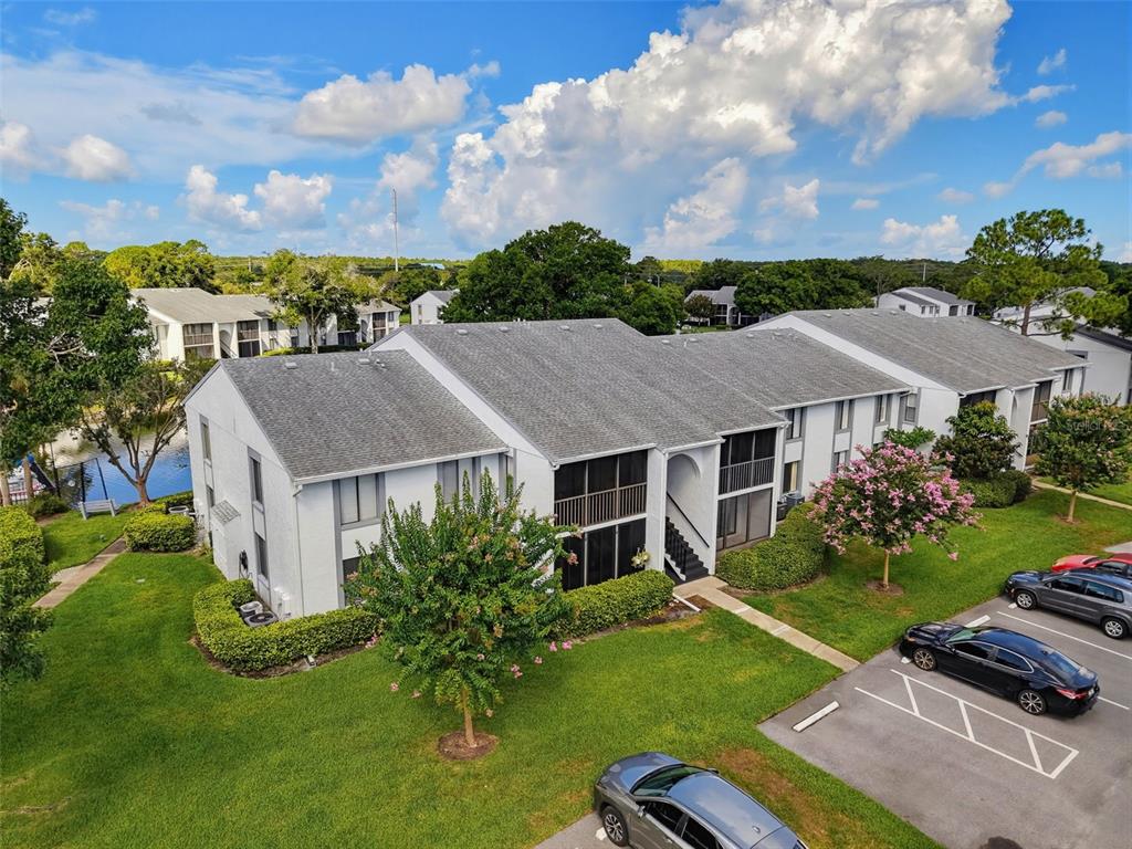 An aerial view of a two-story apartment building with a gray roof and parking lot — 1261 PINE RIDGE CIRCLE W UNIT D1, TARPON SPRINGS, FL
