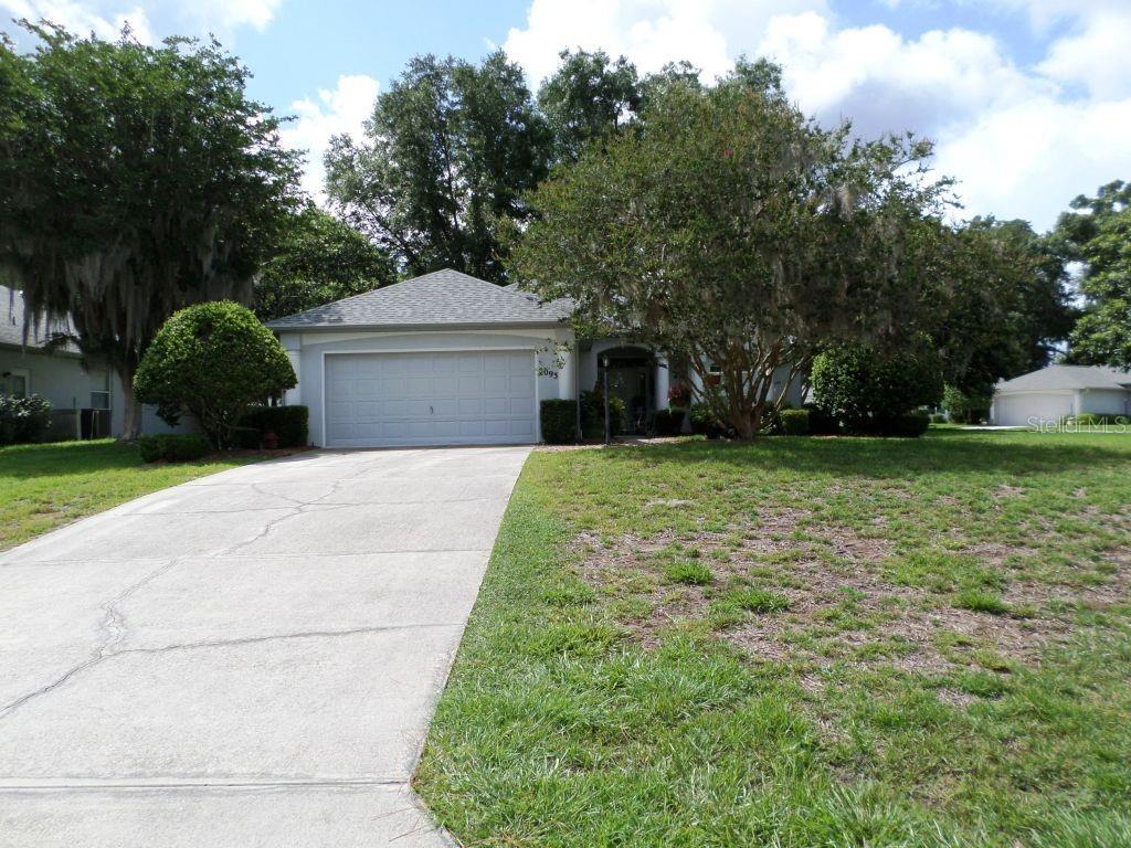 A single-story house with a two-car garage and a concrete driveway sits on a lawn — 9093 SW 192ND COURT RD, DUNNELLON, FL