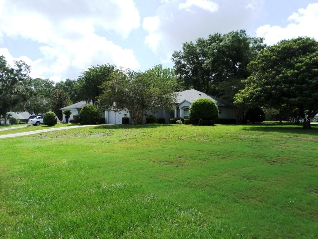 A single-story house with a large front lawn and a driveway sits among mature trees — 9093 SW 192ND COURT RD, DUNNELLON, FL