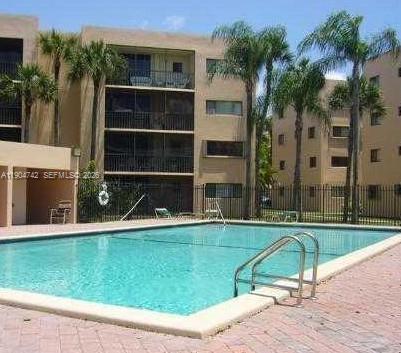 A swimming pool sits in front of a multi-story apartment building with palm trees — 8760 SW 133rd Ave Rd # 318, Miami FL 33183, MIAMI, FL
