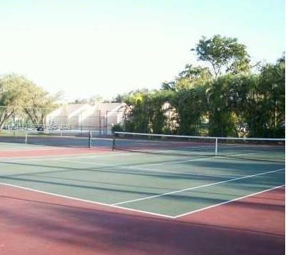 A tennis court with a green surface and white lines surrounded by trees and fencing — 8760 SW 133rd Ave Rd # 318, Miami FL 33183, MIAMI, FL
