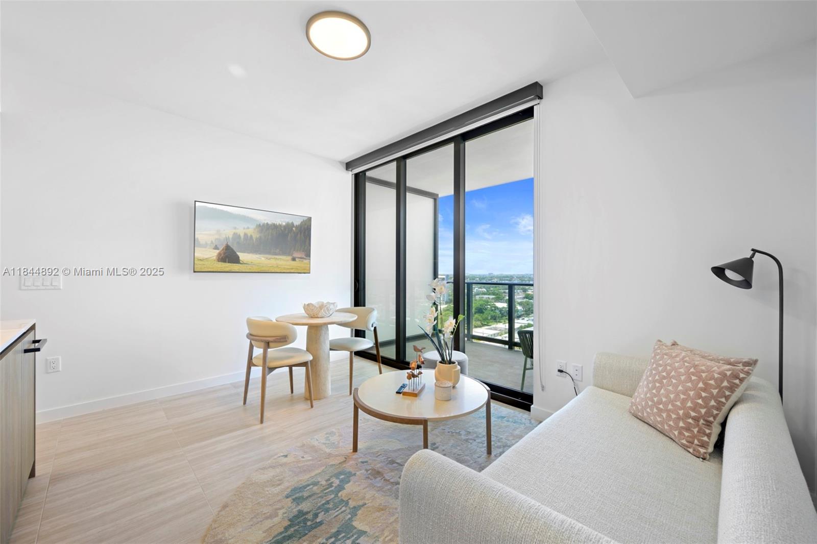 A bright living area features a sofa, dining set, and a balcony with city views — 580 72nd St # 1603, Miami Beach FL 33141, MIAMI BEACH, FL
