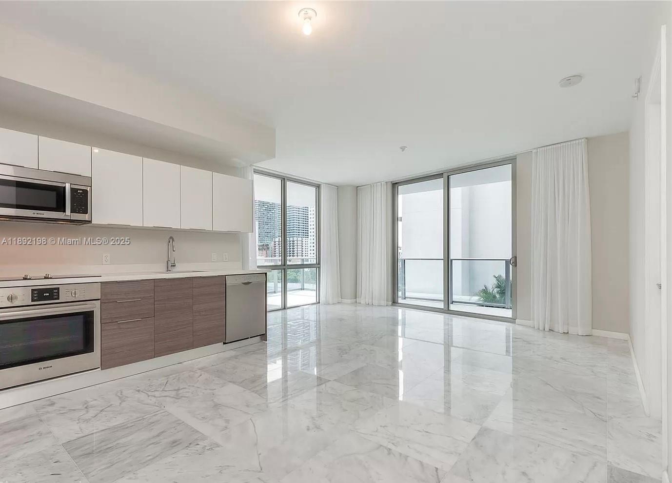 A modern kitchen and living area feature white cabinets, wood-toned lower drawers, and marble flooring — 1010 SW 2nd Ave # 603, Miami FL 33130, MIAMI, FL