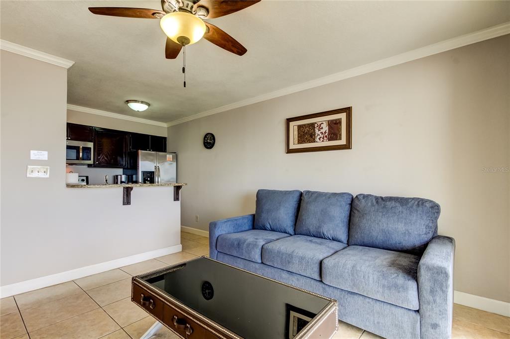 A living room with a blue sofa, coffee table, and an open kitchen in the background — 2506 N ROCKY POINT DRIVE UNIT 457, TAMPA, FL