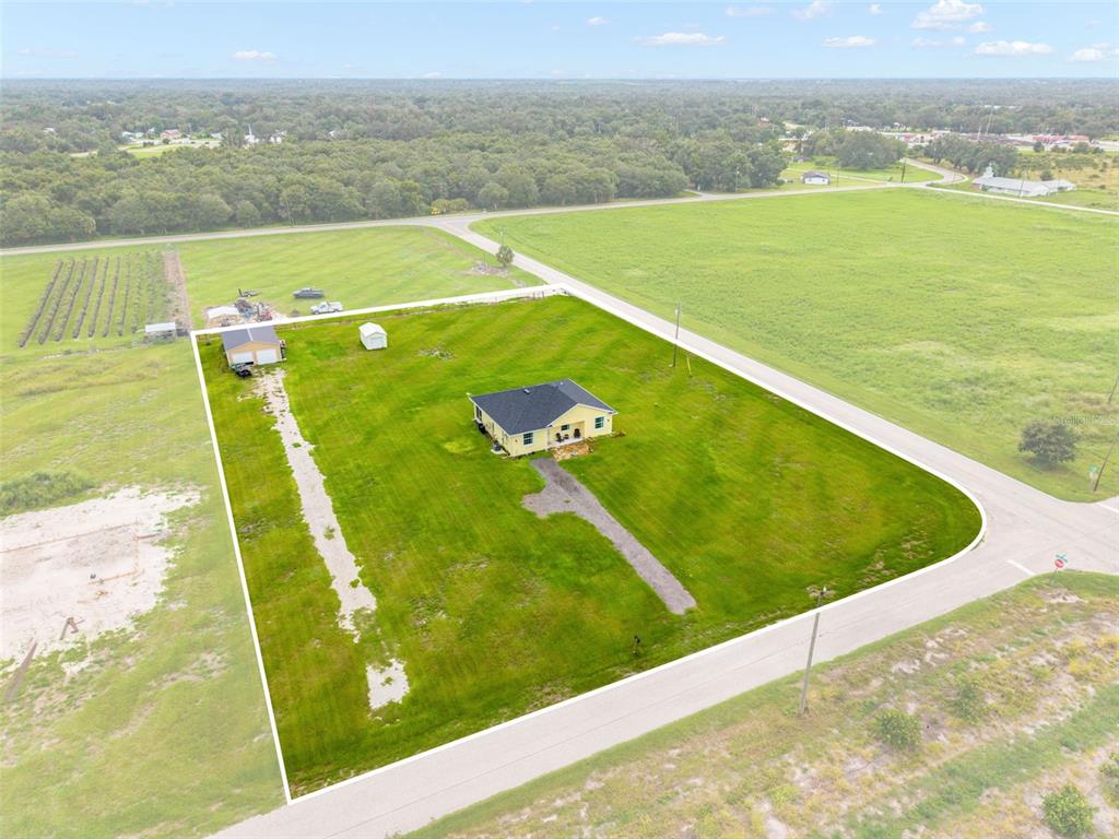 An aerial view shows a yellow house with a detached garage on a large lot — 4651 SW PROVAU AVENUE, ARCADIA, FL