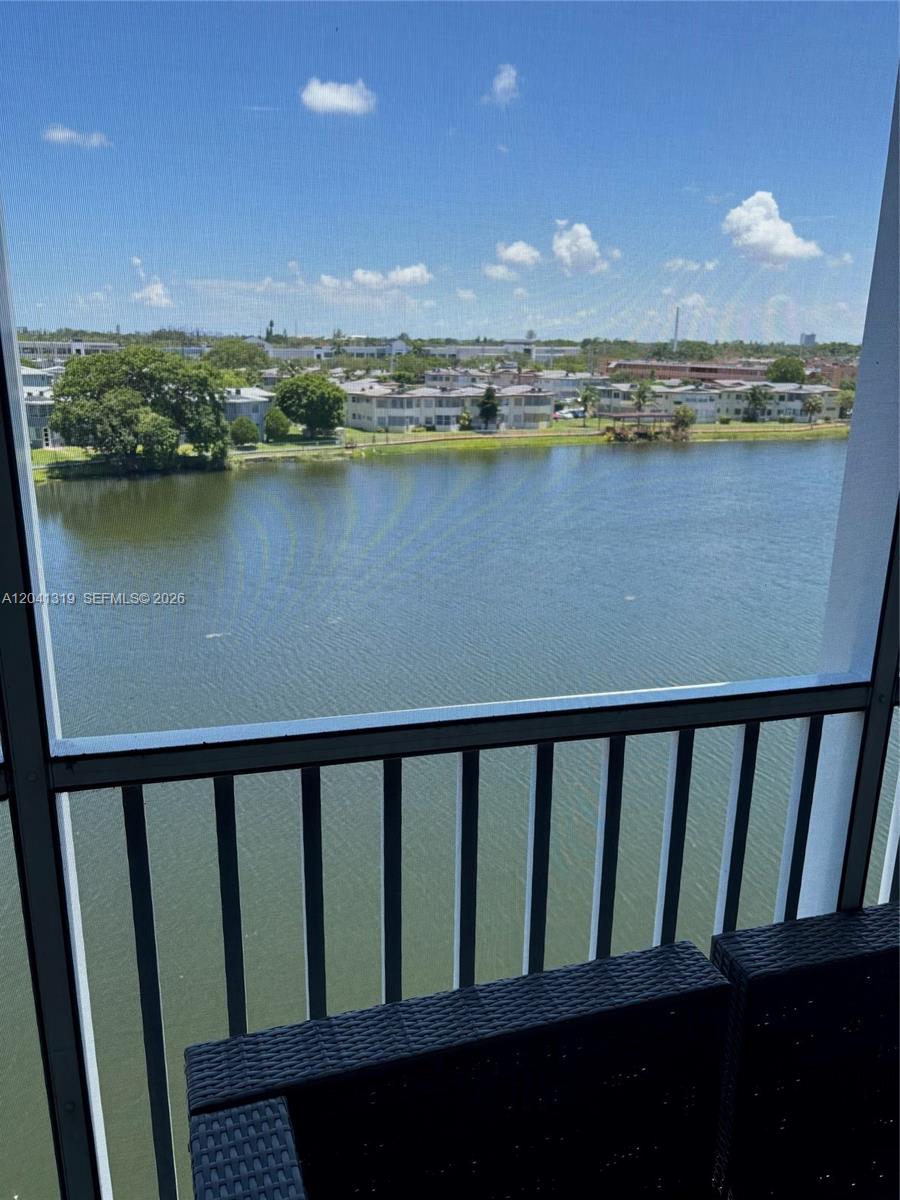A balcony with a black metal railing overlooks a lake and residential buildings — 1750 NE 191st St # 4, Miami FL 33179, MIAMI, FL