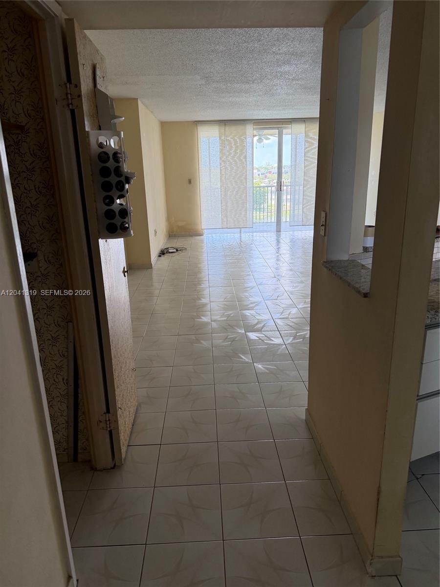 A tiled hallway leads to a living area with a balcony and floor-to-ceiling windows — 1750 NE 191st St # 4, Miami FL 33179, MIAMI, FL