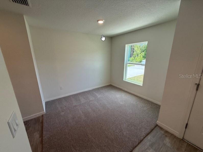 An empty bedroom features beige carpet, light-colored walls, a single window, and a ceiling light — 1 RIVERVIEW PLACE, PALM COAST, FL