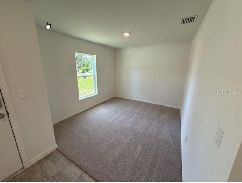 An empty bedroom features beige carpet, white walls, a single window, and a ceiling light — 1 RIVERVIEW PLACE, PALM COAST, FL