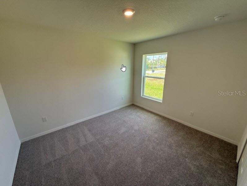 An empty bedroom features neutral walls, gray carpeting, a single window, and a ceiling light — 1 RIVERVIEW PLACE, PALM COAST, FL