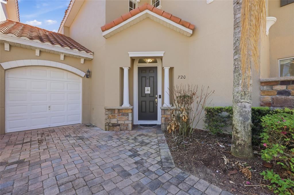 The exterior of a home features a paved driveway, a garage, and a front entrance — 720 BRUNELLO DRIVE, DAVENPORT, FL