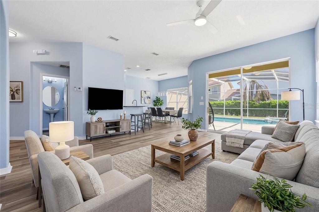 A living room with light blue walls, wood-look flooring, and a view of a pool — 720 BRUNELLO DRIVE, DAVENPORT, FL