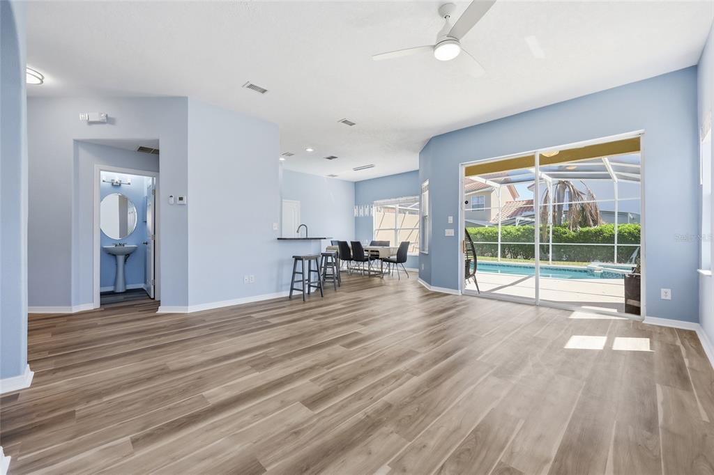 An open-concept living area with light blue walls, wood-look flooring, and a view of a pool — 720 BRUNELLO DRIVE, DAVENPORT, FL