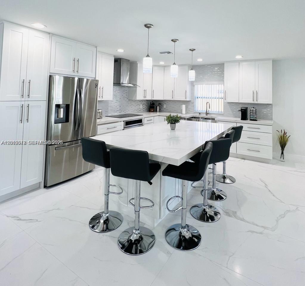 A modern white kitchen features a large marble-topped island with four black bar stools — 218 SE 3rd Pl # 0, Dania Beach FL 33004, DANIA BEACH, FL