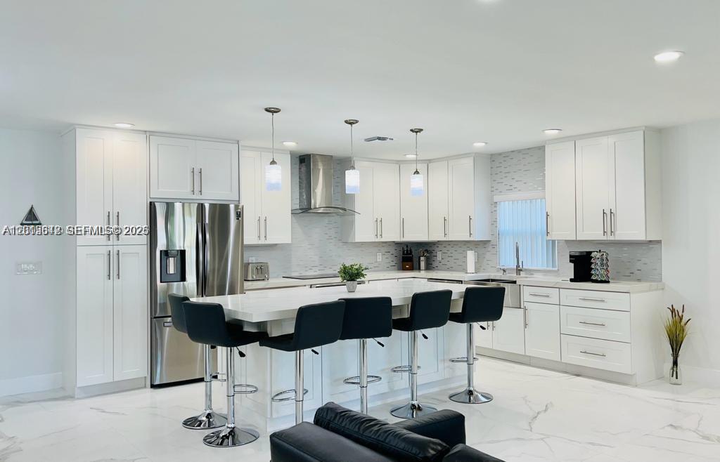 A modern kitchen features white cabinetry, a large island with bar seating, and marble flooring — 218 SE 3rd Pl # 0, Dania Beach FL 33004, DANIA BEACH, FL