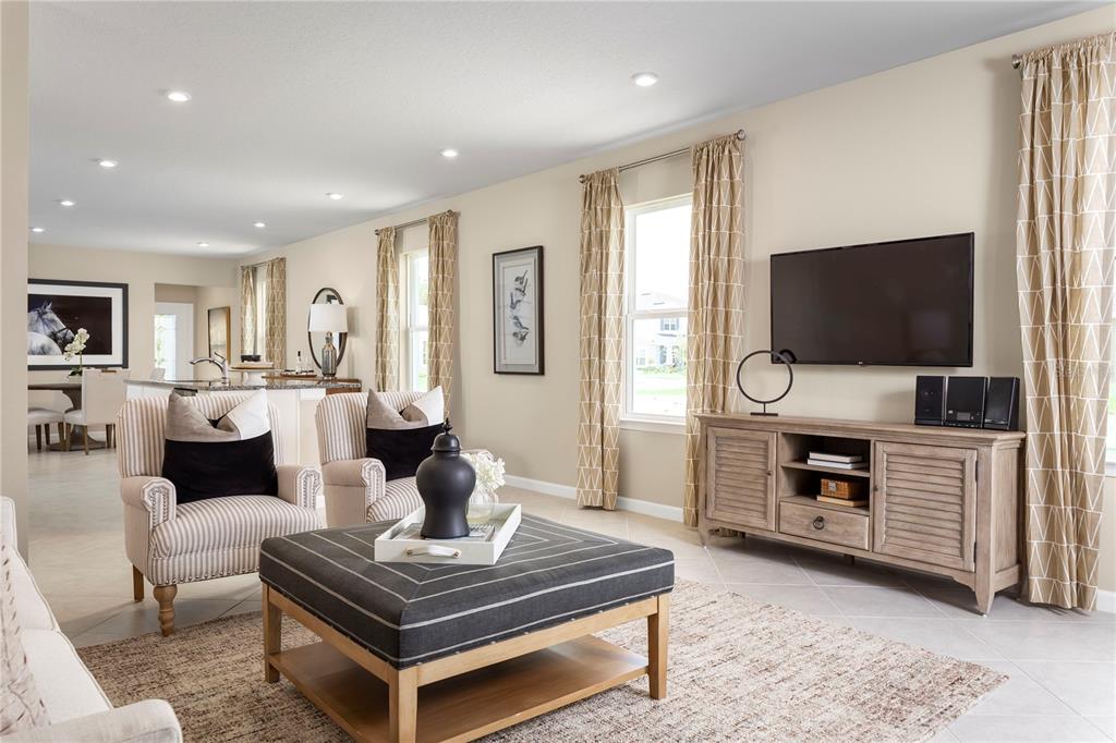 A living room features a television on a wooden console, two armchairs, and an ottoman — 2445 WHITE LADYFISH ROAD, WIMAUMA, FL