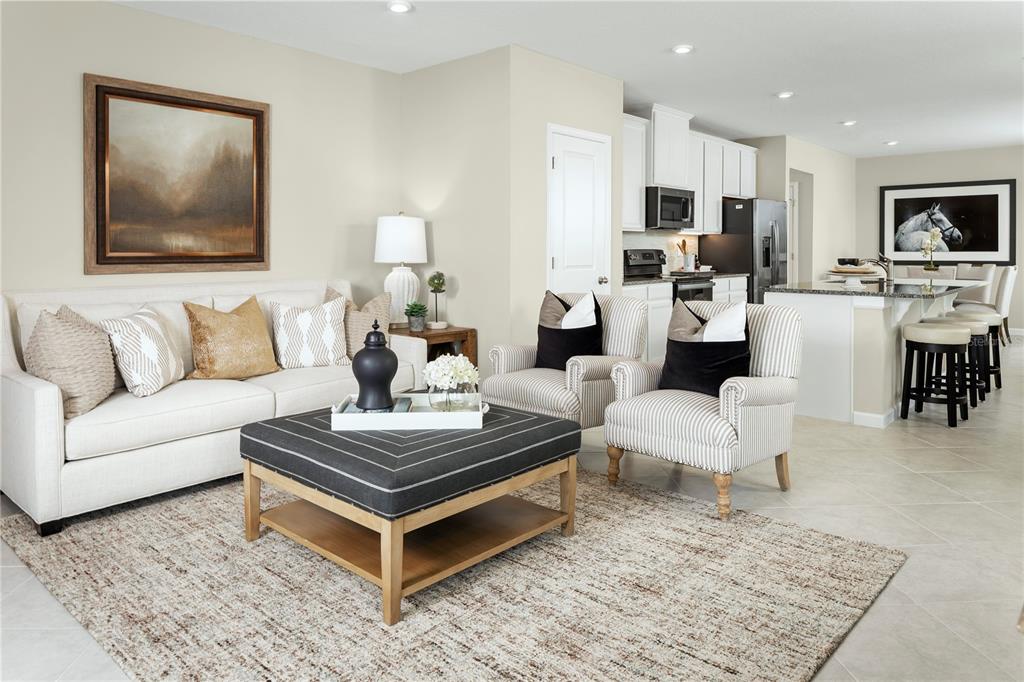 An open-concept living room and kitchen featuring a white sofa, striped armchairs, and kitchen island — 2445 WHITE LADYFISH ROAD, WIMAUMA, FL