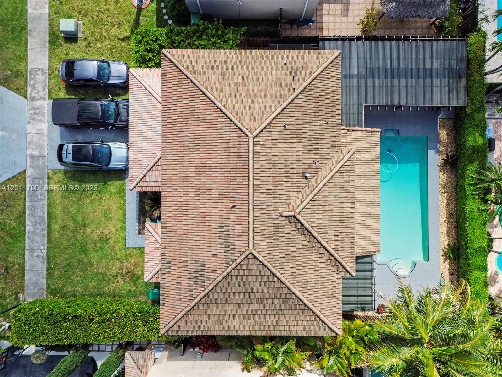 An aerial view shows a house with a tiled roof, a swimming pool, and three parked cars — 16162 SW 143rd St, Miami FL 33196, MIAMI, FL
