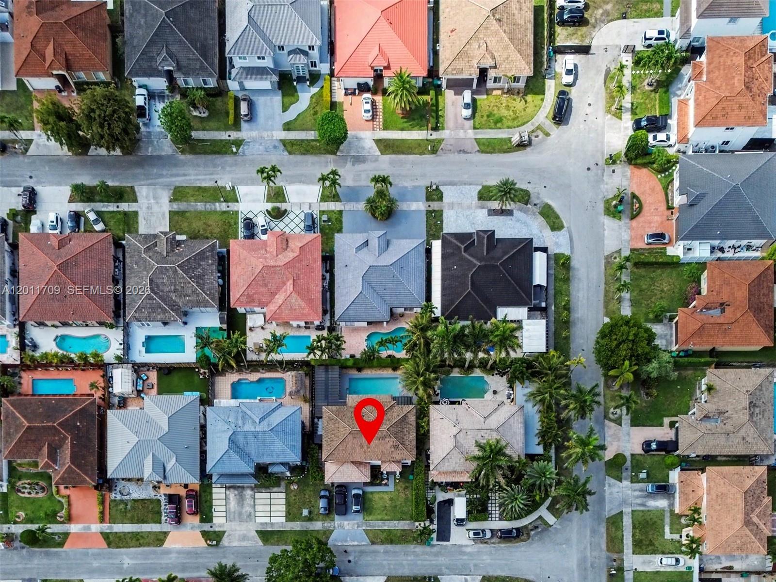 This aerial view shows a suburban neighborhood with houses, swimming pools, and paved streets — 16162 SW 143rd St, Miami FL 33196, MIAMI, FL