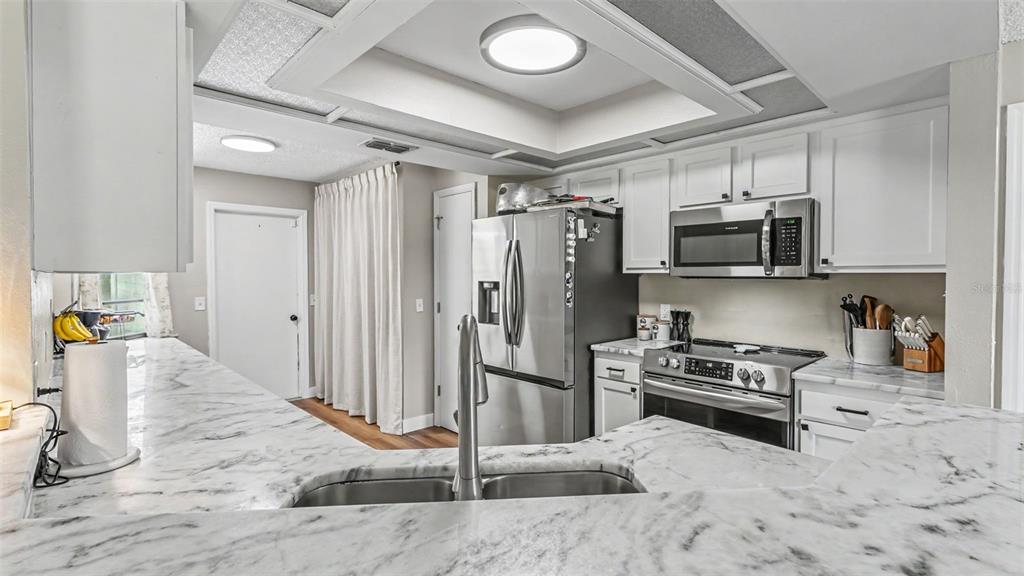 A kitchen features white cabinets, stainless steel appliances, and a marble-patterned countertop with a sink — 5303 KNIGHTS STATION ROAD, LAKELAND, FL