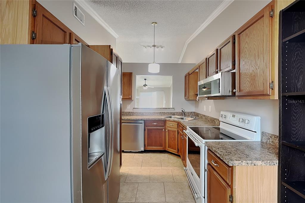 A kitchen with wood cabinets, stainless steel appliances, and a pass-through window to another room — 111 HIDDEN ARBOR COURT, SANFORD, FL