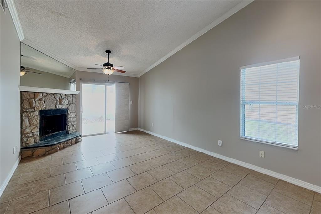 A living room features tile flooring, a stone fireplace, a ceiling fan, and sliding doors — 111 HIDDEN ARBOR COURT, SANFORD, FL