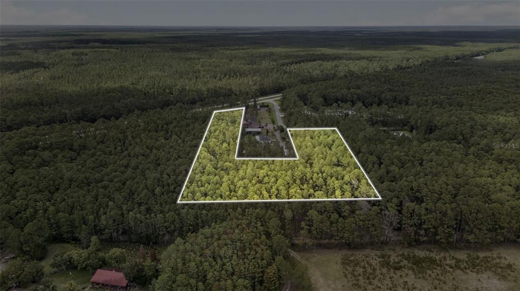 An aerial view shows a wooded lot outlined in white situated near a rural road — HWY 92 AT BIG JOHN RD, DELAND, FL