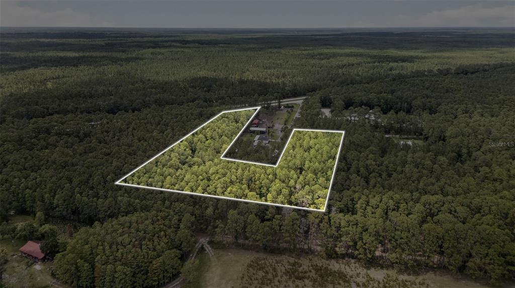 An aerial view shows a wooded lot outlined in white with a house nearby — HWY 92 AT BIG JOHN RD, DELAND, FL