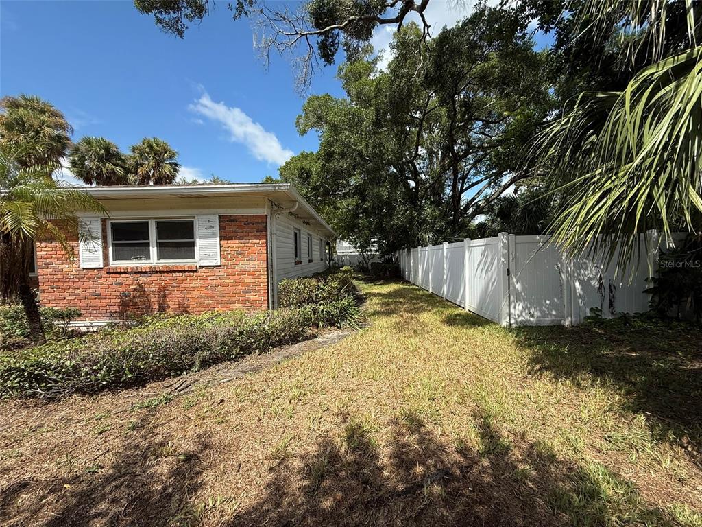 A brick house exterior features a white fence along a grassy side yard — 215 S WEST SHORE BOULEVARD, TAMPA, FL