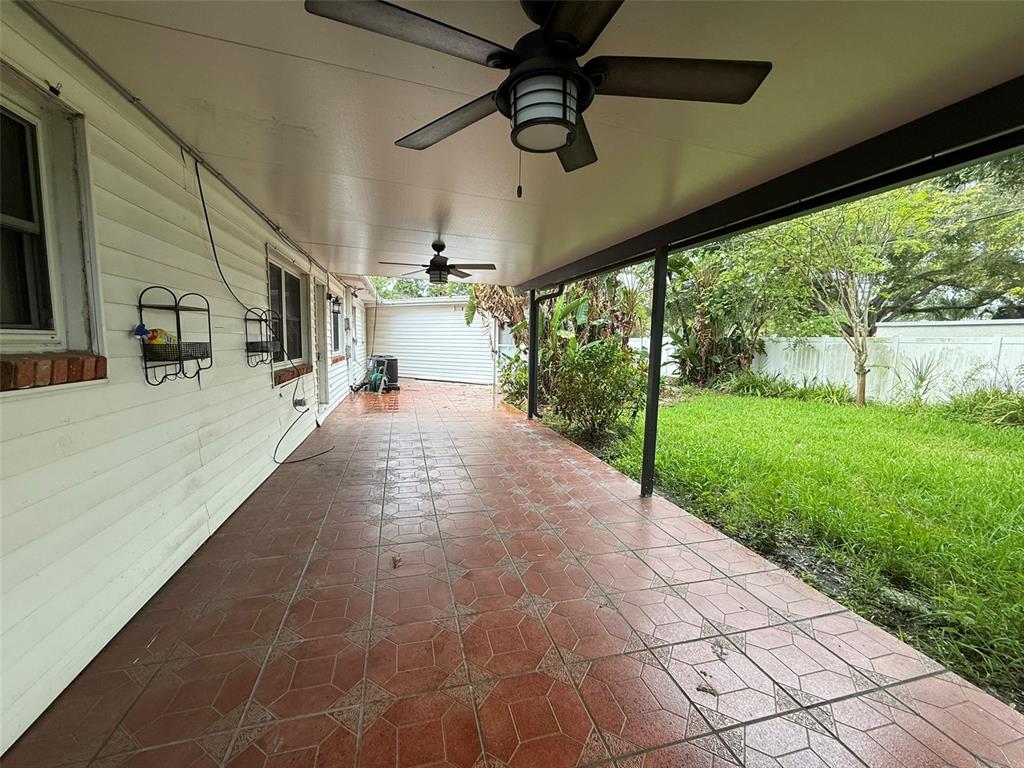 A covered patio features red tiled flooring, two ceiling fans, and a view of the yard — 215 S WEST SHORE BOULEVARD, TAMPA, FL